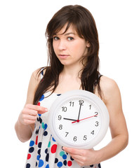 Young woman is holding big clock