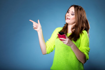 Happy girl with mobile phone pointing