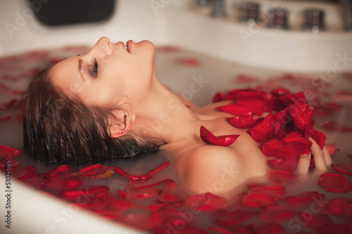Fototapeta do kuchni Woman in bath at spa in milk with roses petals