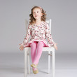Photo of fashionable sweet little girl posing on the white chair