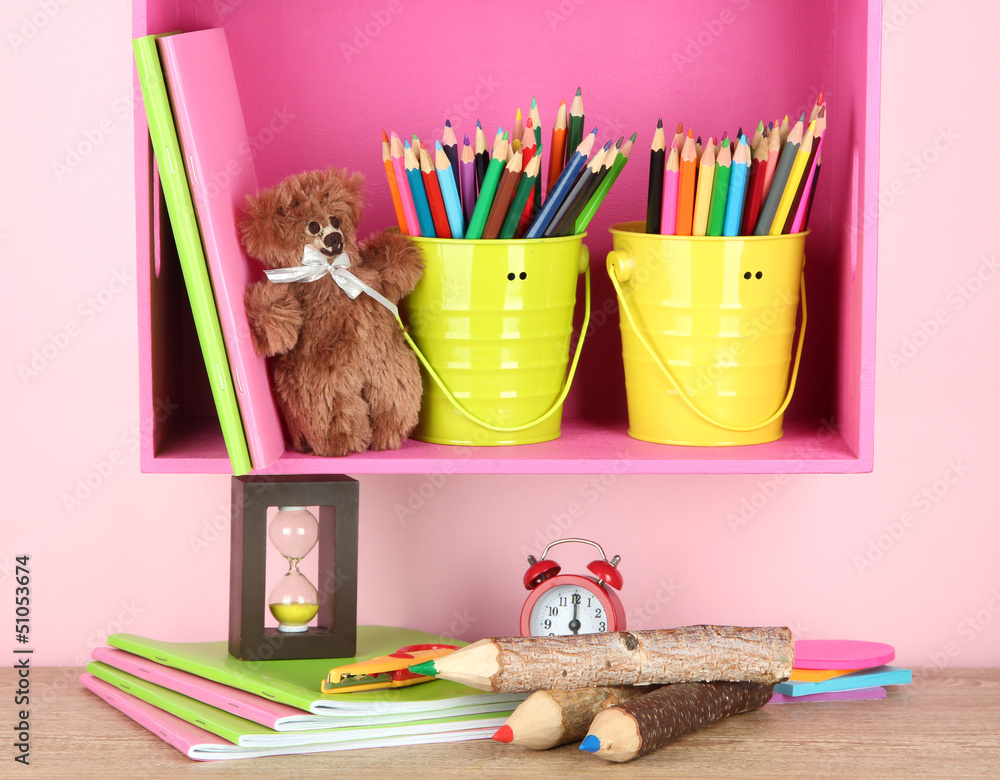 Colorful pencils in pails on shelf on beige background