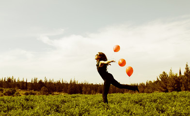 Young woman with red balloons on the field