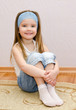Smiling little girl sitting on a house floor