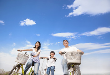 Wall Mural - happy family riding bicycle with cloud background