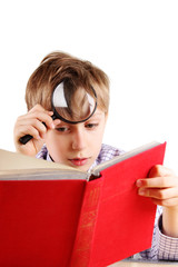 Blond boy reading a bright hardcover book with a magnifying glas