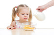 kid girl eating corn flakes with milk over white