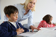 © goodluz - Teacher looking at classbook with young boy