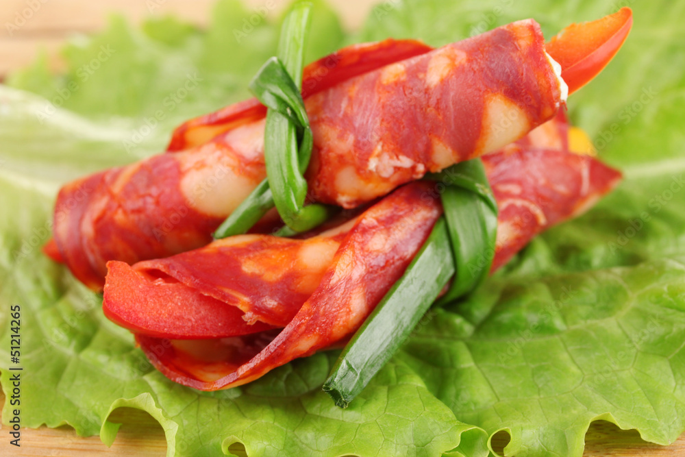 Salami rolls on wooden board, close up