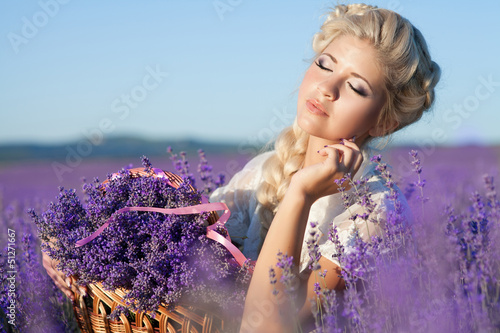 Fototapeta na wymiar Beautiful blonde woman with lavendar in blossom field