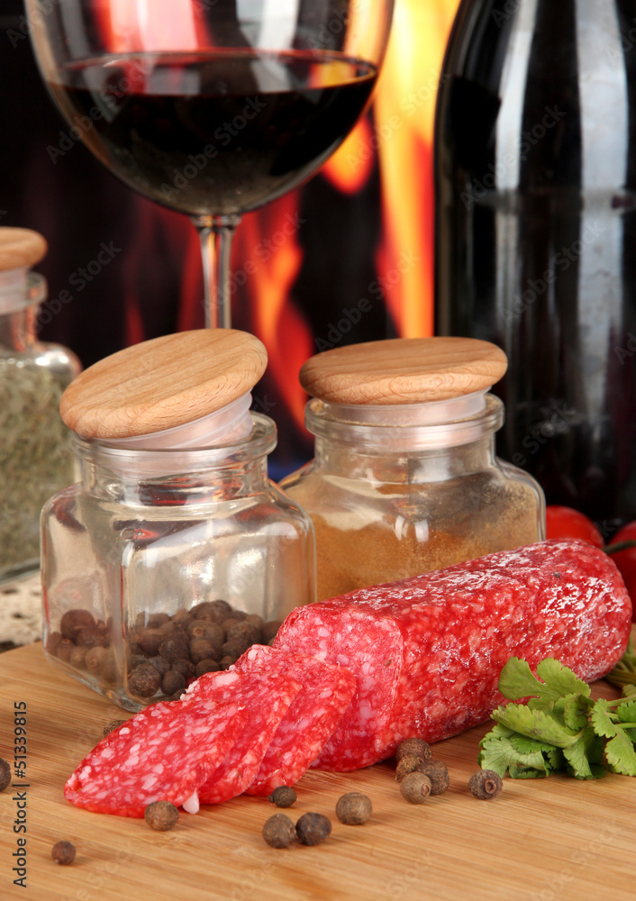 Tasty salami on board wooden table on fire background