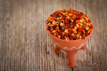 Dried red pepper flakes on rustic wooden plank