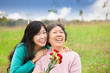© Tom Wang - Smiling daughter and her mother with carnation flower on the gra