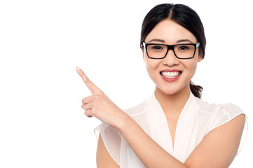 Smiling girl wearing eyeglasses pointing away