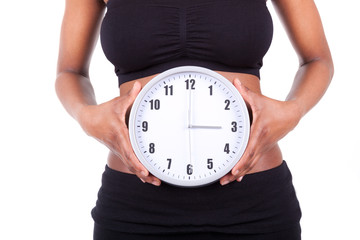 Wall Mural - Young black african american woman holding a clock in front of h