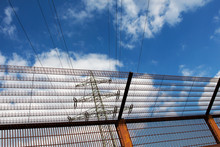 Electricity Pylon And Barrier Fence Against  Blue Sky
