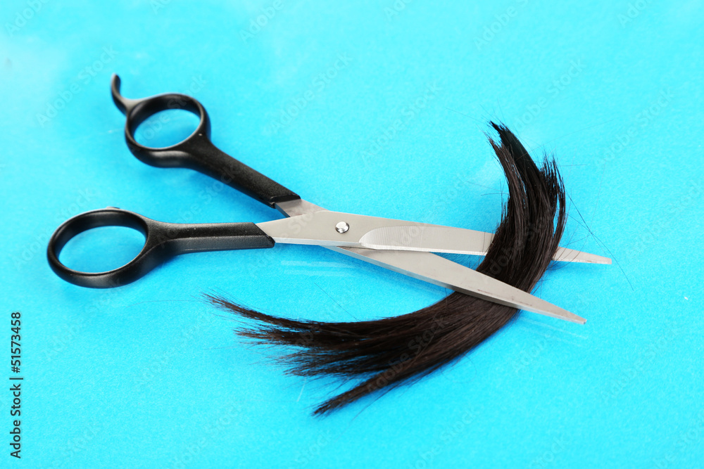 Pieces of hair cut with scissors on blue background