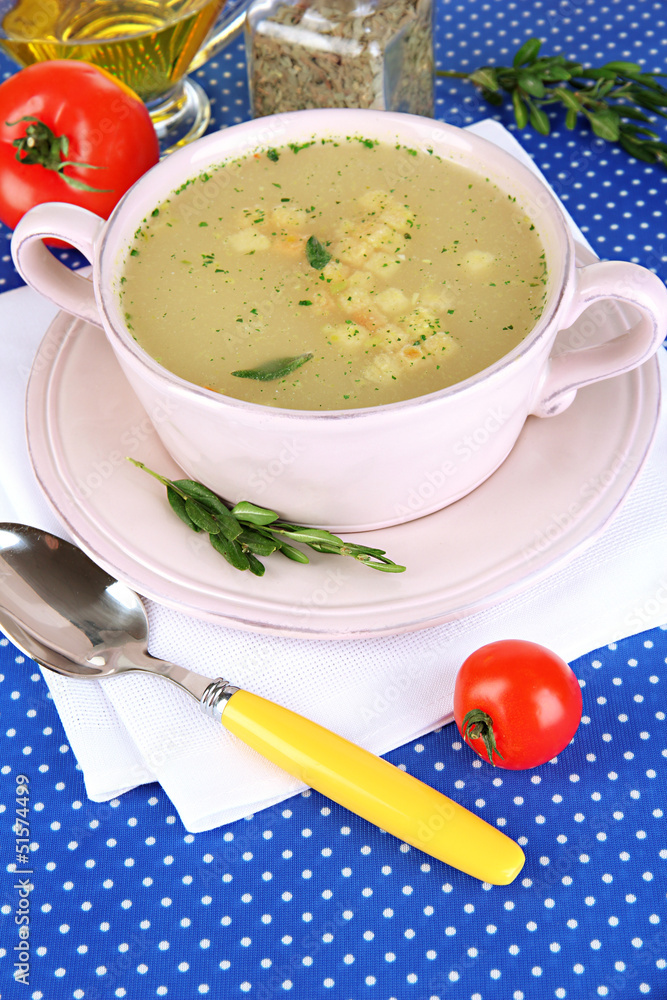 Nourishing soup in pink pan on blue tablecloth close-up