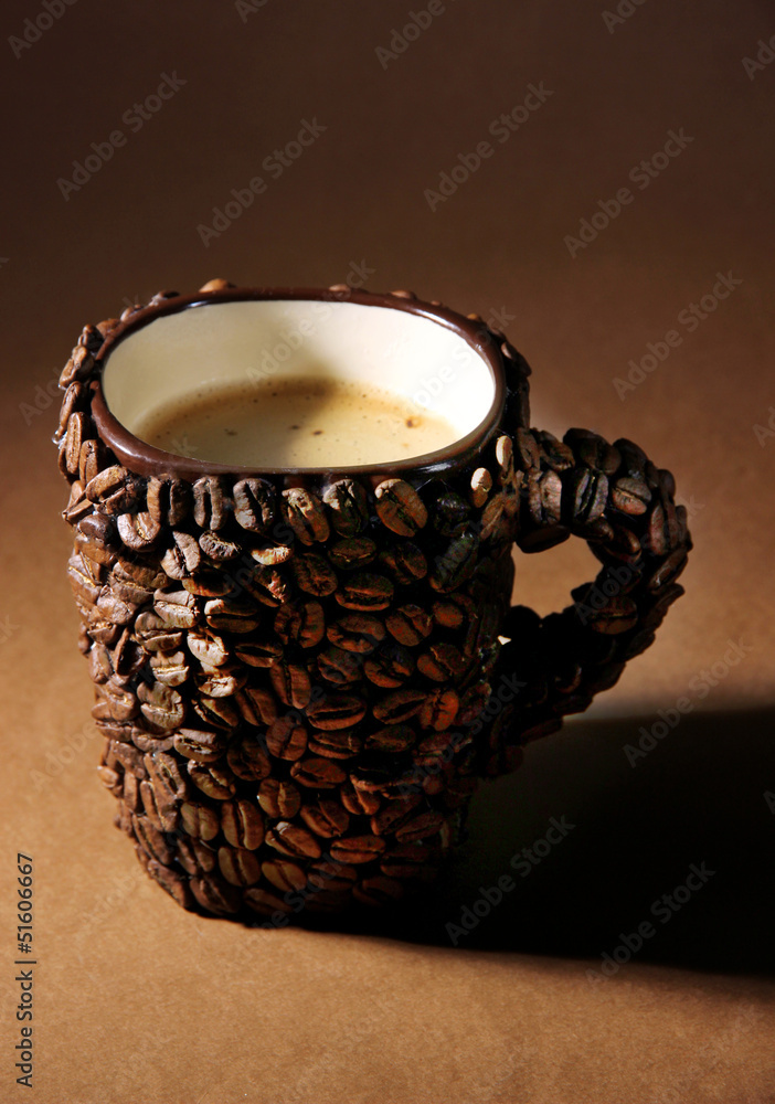 Cup of coffee beans, on brown background