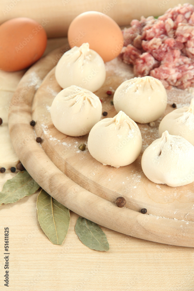 Raw dumplings and ingredients on wooden table