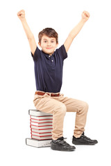 A happy school boy raised his hands gesturing happiness, seated