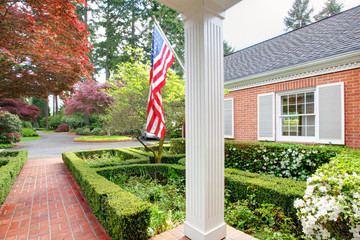 Wall Mural - American old brick home with flag and classic garden.