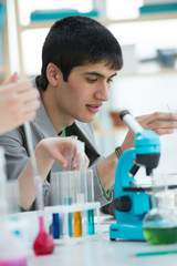 male student working with microscope and different liquids in sc