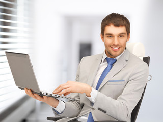 Canvas Print - young businessman sitting in chair with laptop