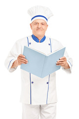 Wall Mural - A mature chef holding a cookbook and looking at camera