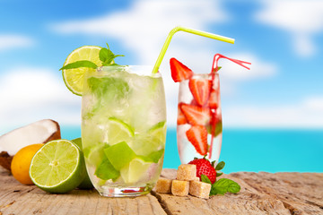 Canvas Print - Fresh summer drinks on wooden table with blur sea background