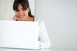 © pablocalvog - Charming young woman reading on laptop screen