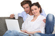 © auremar - Couple using a laptop on a sofa
