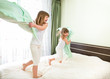 Little girls fighting using pillows in bedroom