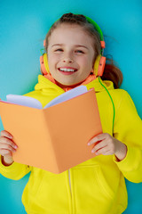 Wall Mural - Young girl in headphones reading a book