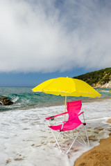 Wall Mural - Yellow parasol and pink chair at the beach