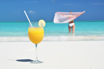 Wall Mural - Glass of orange juice on the sandy beach of Exuma, Bahamas