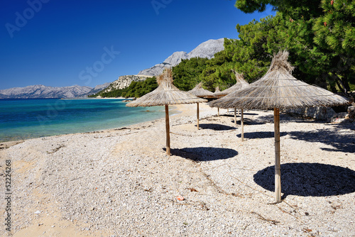 Obraz na płótnie canvas Piękna pusta plaża z parasolami w makarska, chorwacja