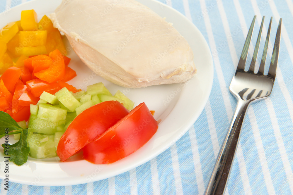 Boiled chicken breast on plate with vegetables close up