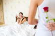 © AlikeYou - man holding a rose behind his back in bedroom