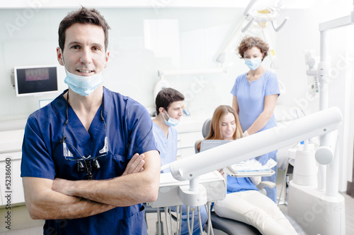 Fototapeta na szkło Portret dentysty z zespołem pracującym w tle