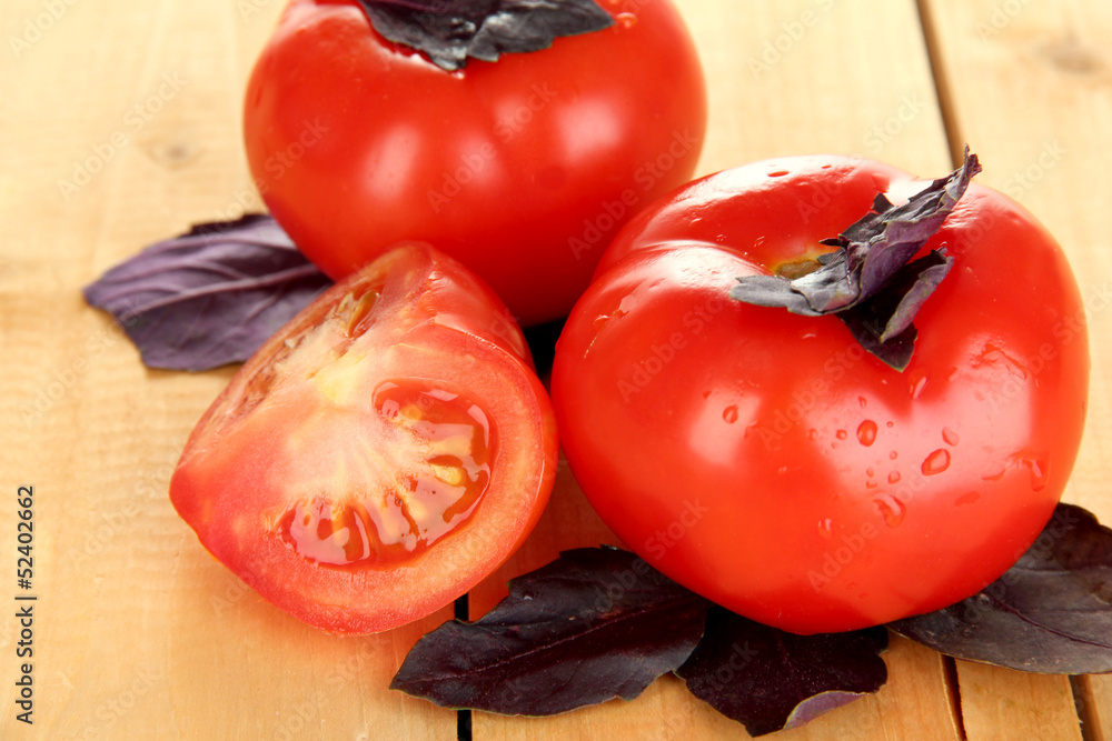 Fresh tomatoes and basil leaves on wooden background