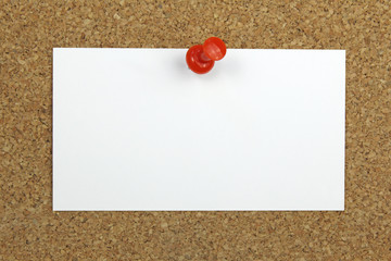 push pin holding a blank note card on a cork board