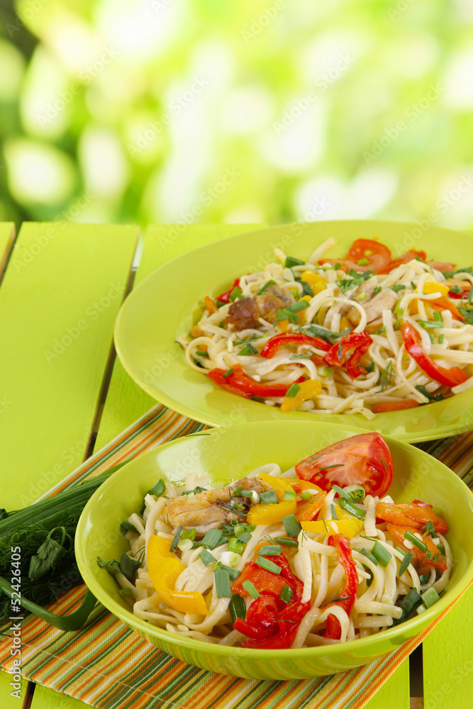 Noodles with vegetables on plates on nature  background