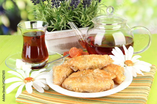 Fotoboard na płycie Słodki baklava na talerzu z herbatą na stole na jasnym tle