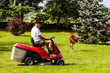 Senior man driving a red lawn mower (tractor)