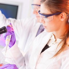 Poster - Young scientist pipetting red solution.