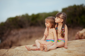 two sisters sitting on a rock and looking into the distance