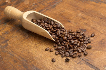 Wall Mural - scoop with coffee beans on wooden table