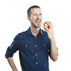 Cheerful beautiful man eating apple, isolated over white backgro