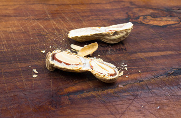 A pile of shelled big peanuts with one cracked open on white bac