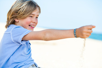 Smiling boy playing with sea sand.